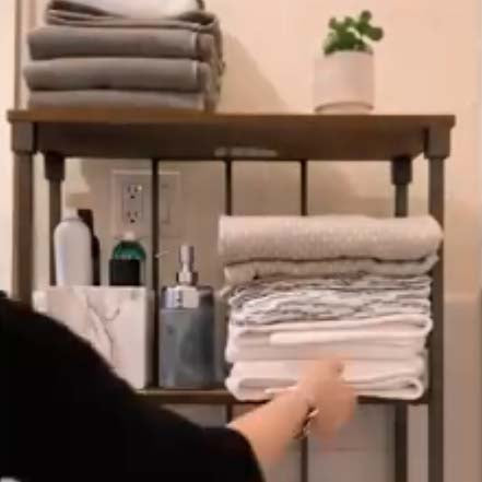 adding towels to a bathroom shelf for room makeover